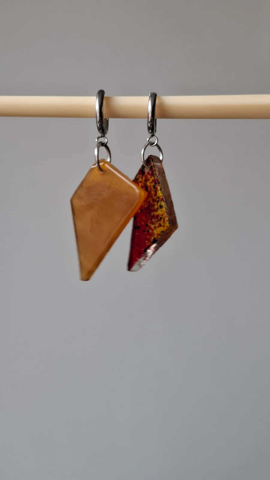 Paire de boucles d'oreilles pendantes asymétriques en verre jaune orangé et rouge moucheté suspendues.