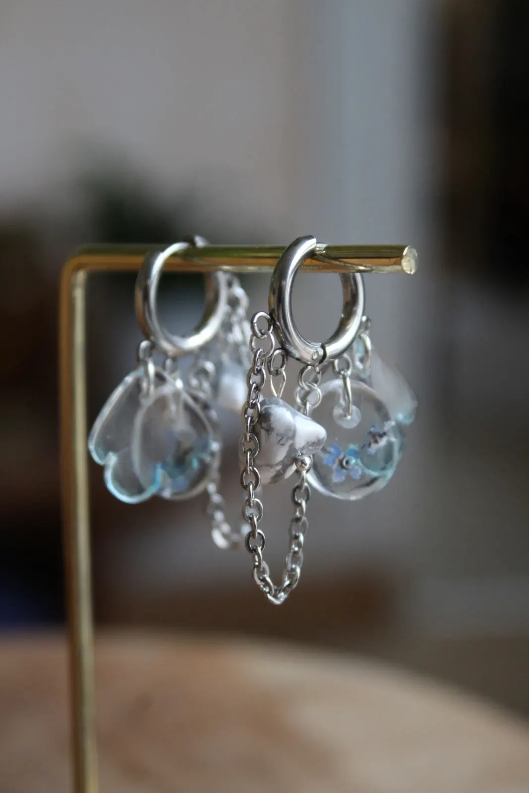 Paire de créoles argentées suspendues avec pendentifs transparents, pierre blanche et chaînette.