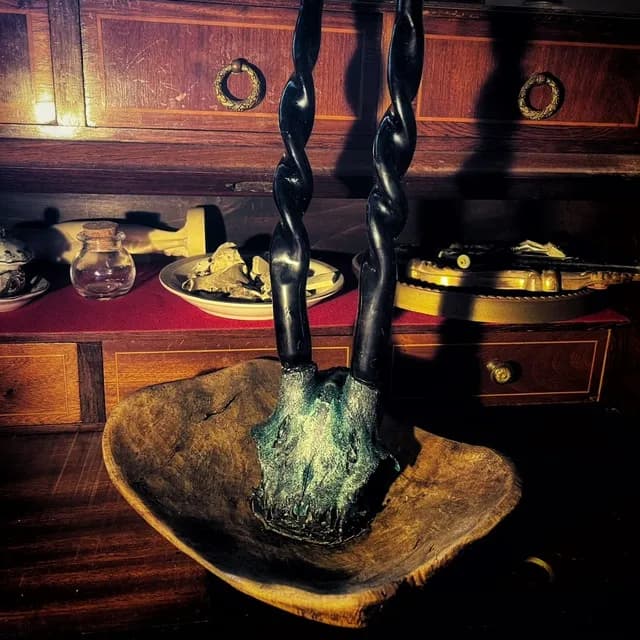 Bougeoir rituel orné d'un crâne texturé vert et noir avec deux bougies torsadées dans une coupelle en bois brut.