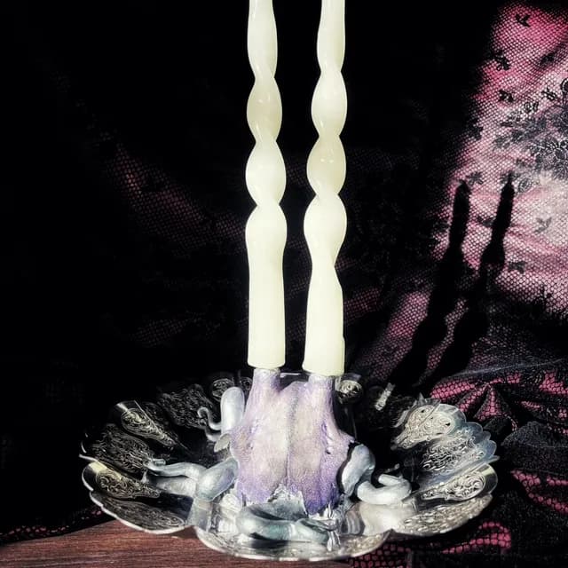 Bougeoir avec massacre de chevreuil teinté violet, deux bougies torsadées et coupelle ouvragée argentée.