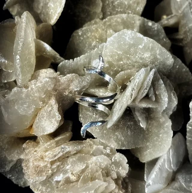 Bague spirale argentée posée sur une formation minérale cristalline