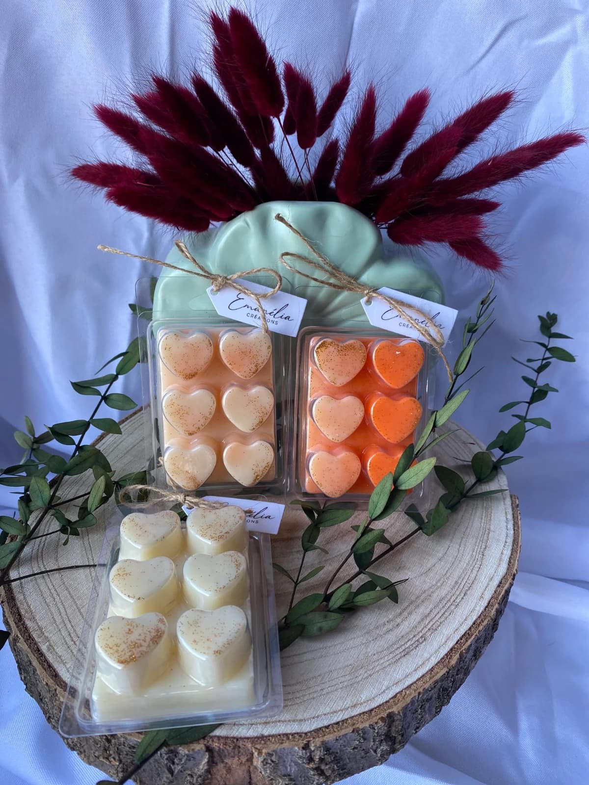 Vue d'ensemble des clamshells de cire parfumée en cœurs aux nuances crème et orangées.